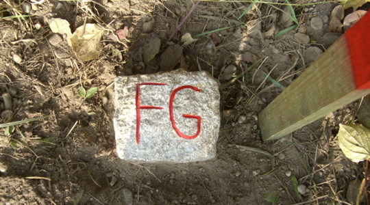 Buchstaben FG eingemeißelt und rot mit Farbe nachgezogen in einen Grenzstein zur Kennzeichnung einer Fischereigrenze